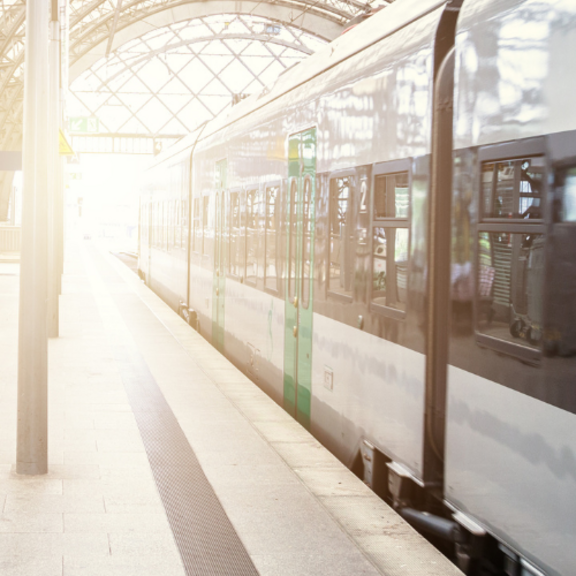A train stood still at a station with sunlight peering through in the distance