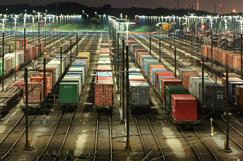 An image of a freight situated along illuminated tracks at night.