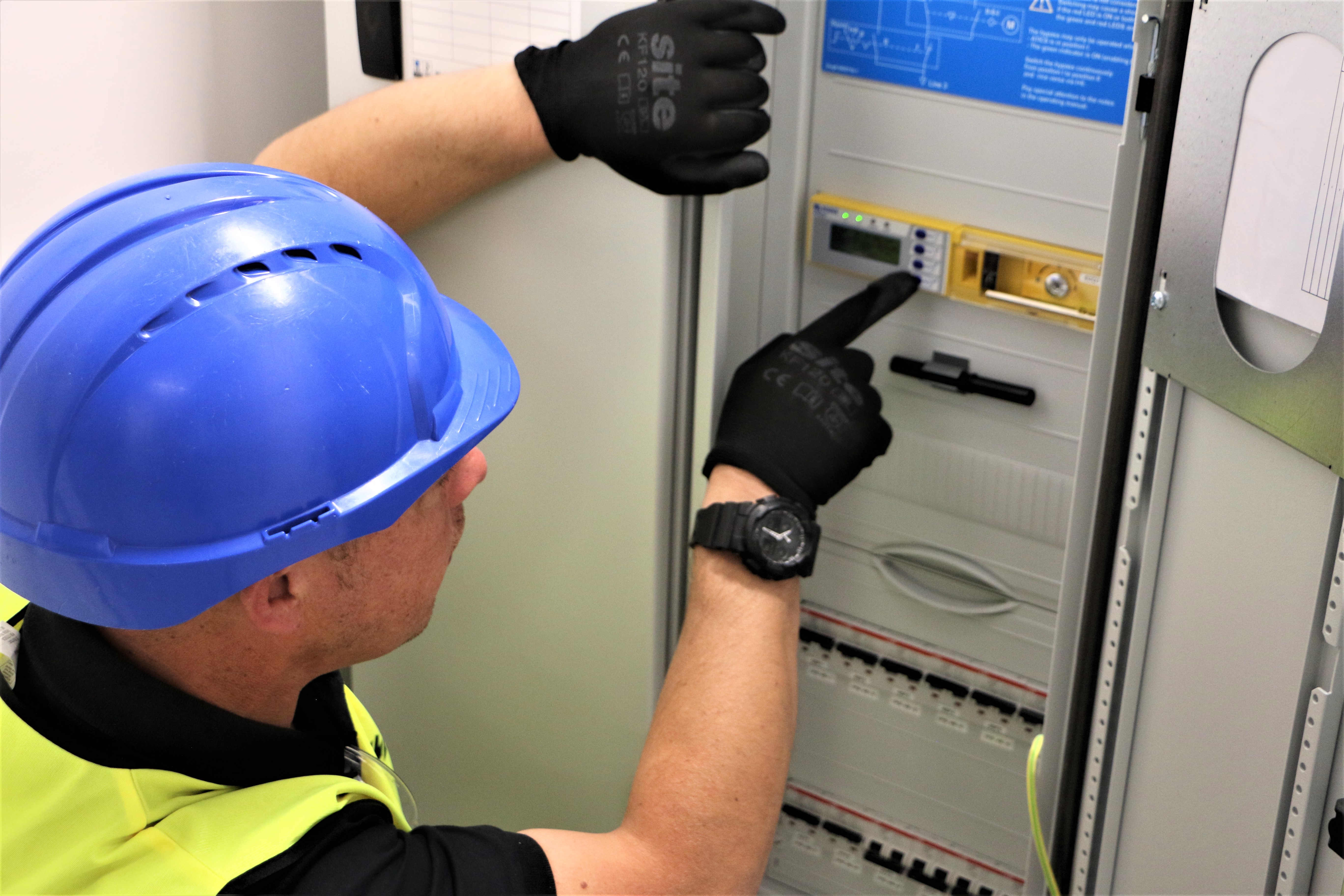 Engineer in personal protective equipment (PPE) assessing a medical IT system installation in a hospital plant-room environment.