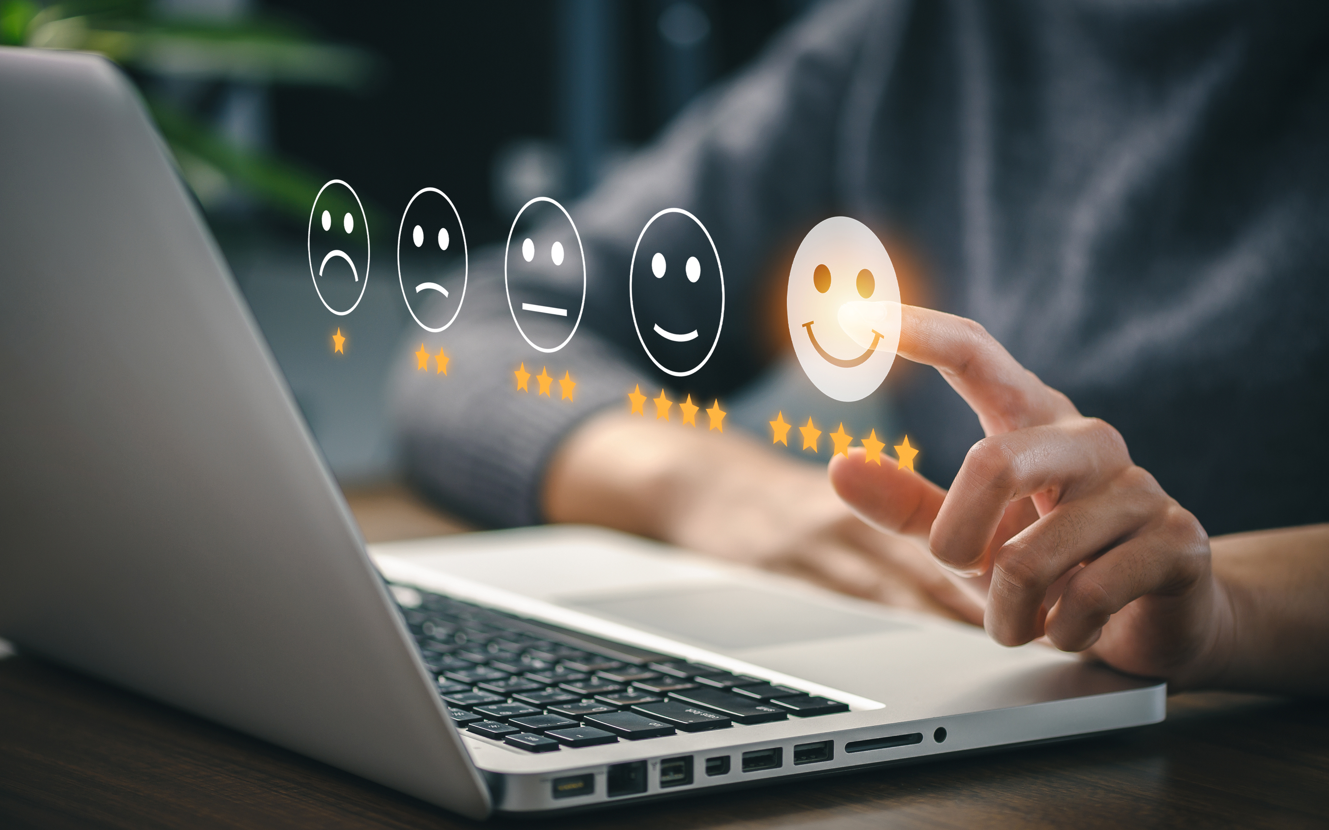 Image of a laptop in the background with stars and smiley face visualizations emerging from the screen, as a customer selects the 5-star rating for satisfaction.