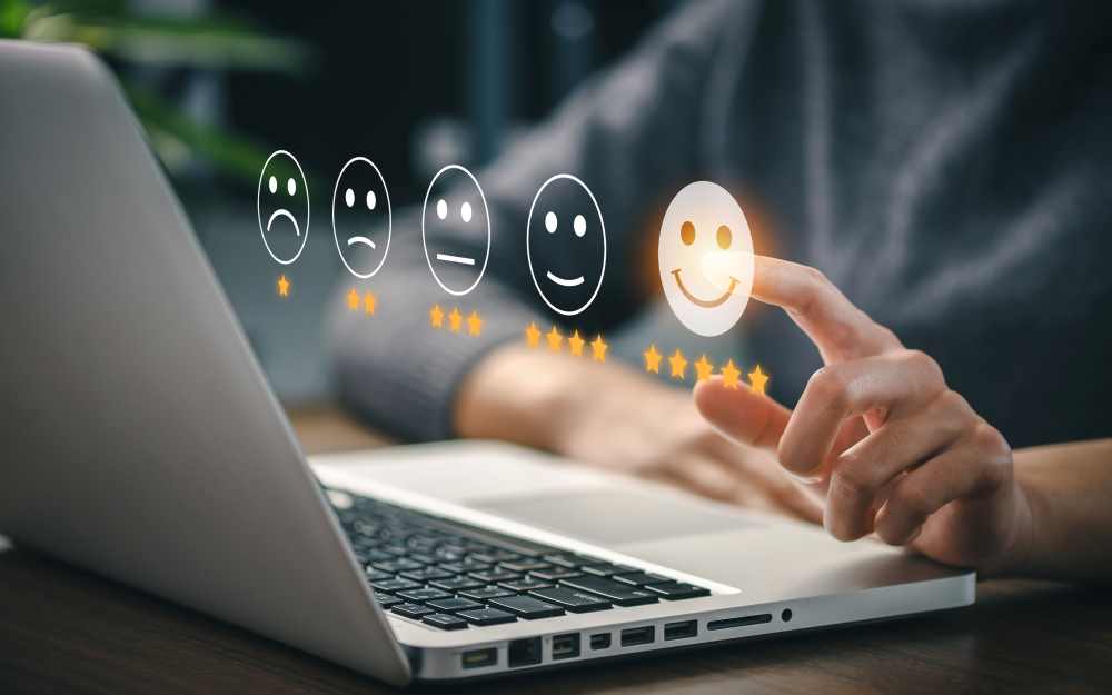 Image of a laptop in the background with stars and smiley face visualizations emerging from the screen, as a customer selects the 5-star rating for satisfaction.