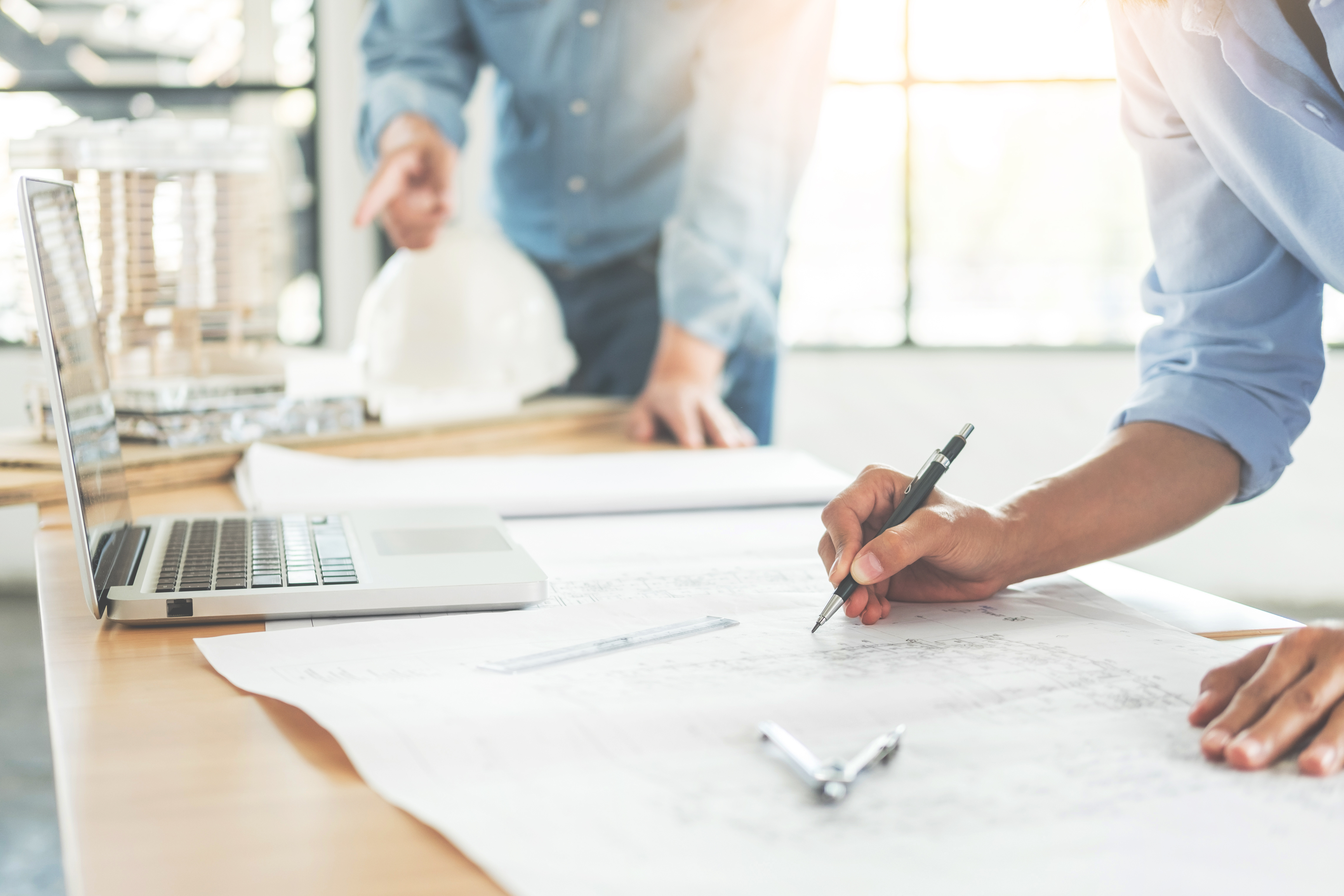 Consultants designing systems with laptops and mapping it out on paper