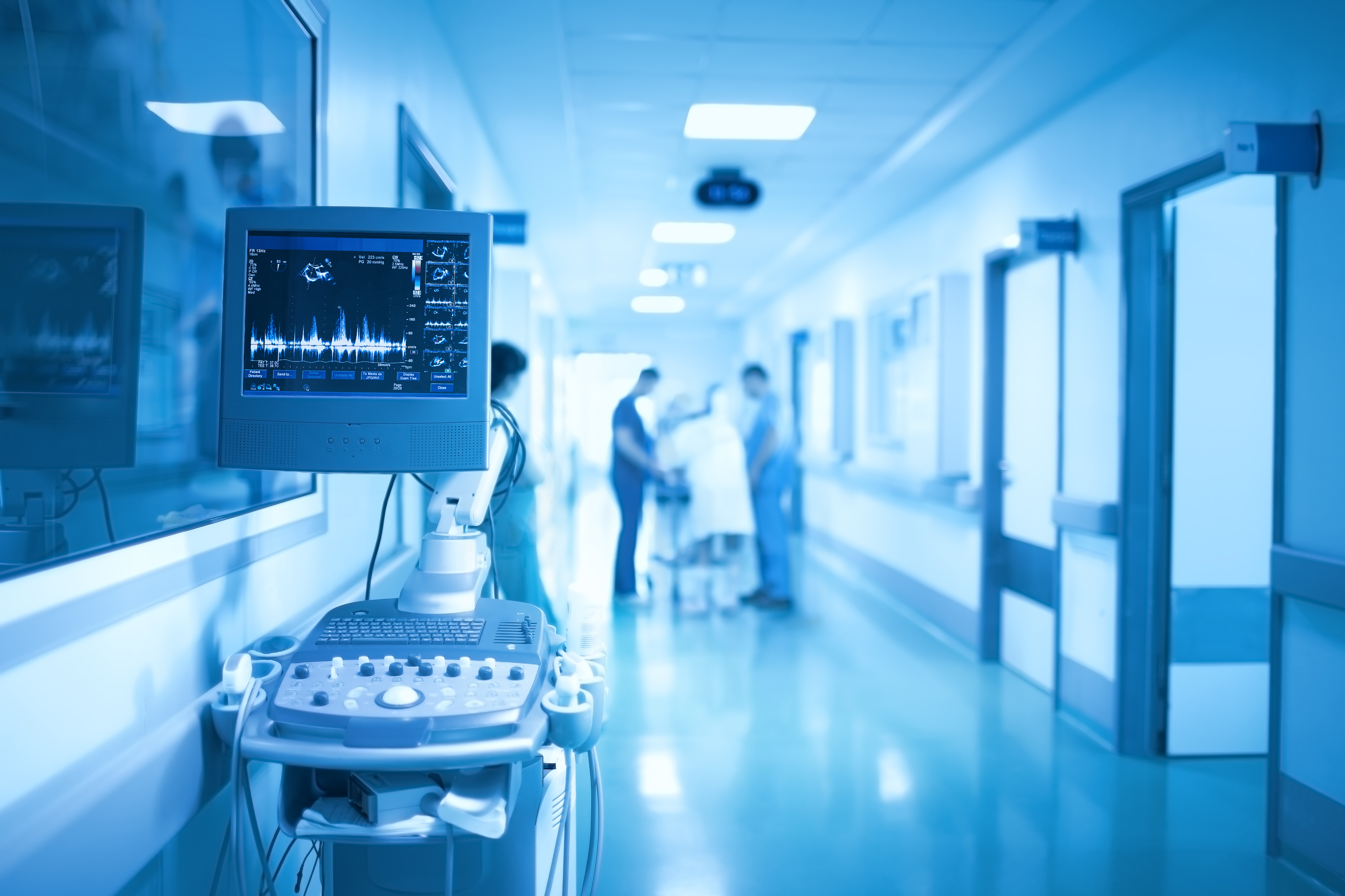 Dark hospital corridor with theatre heart rate machine running and hospital staff working