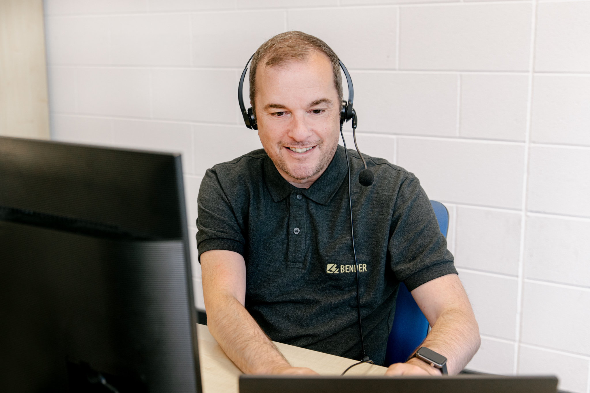 An image of a Bender UK customer service employee with a computer and headset