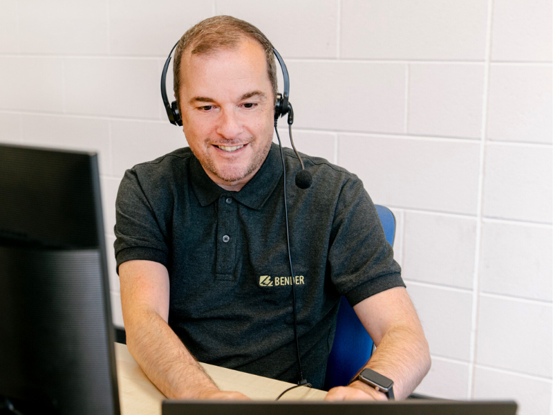 Image of customer relations co-ordinator at a desk answering a query wearing a headset