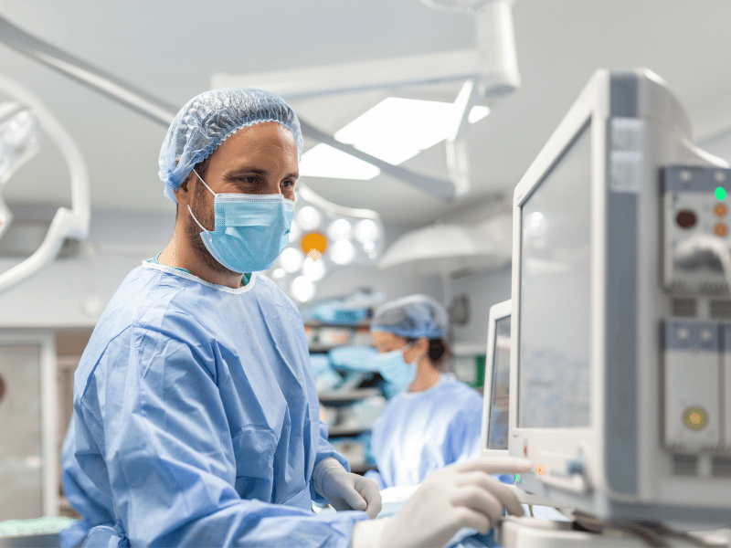 Surgeon in operating room examining electrical medical equipment