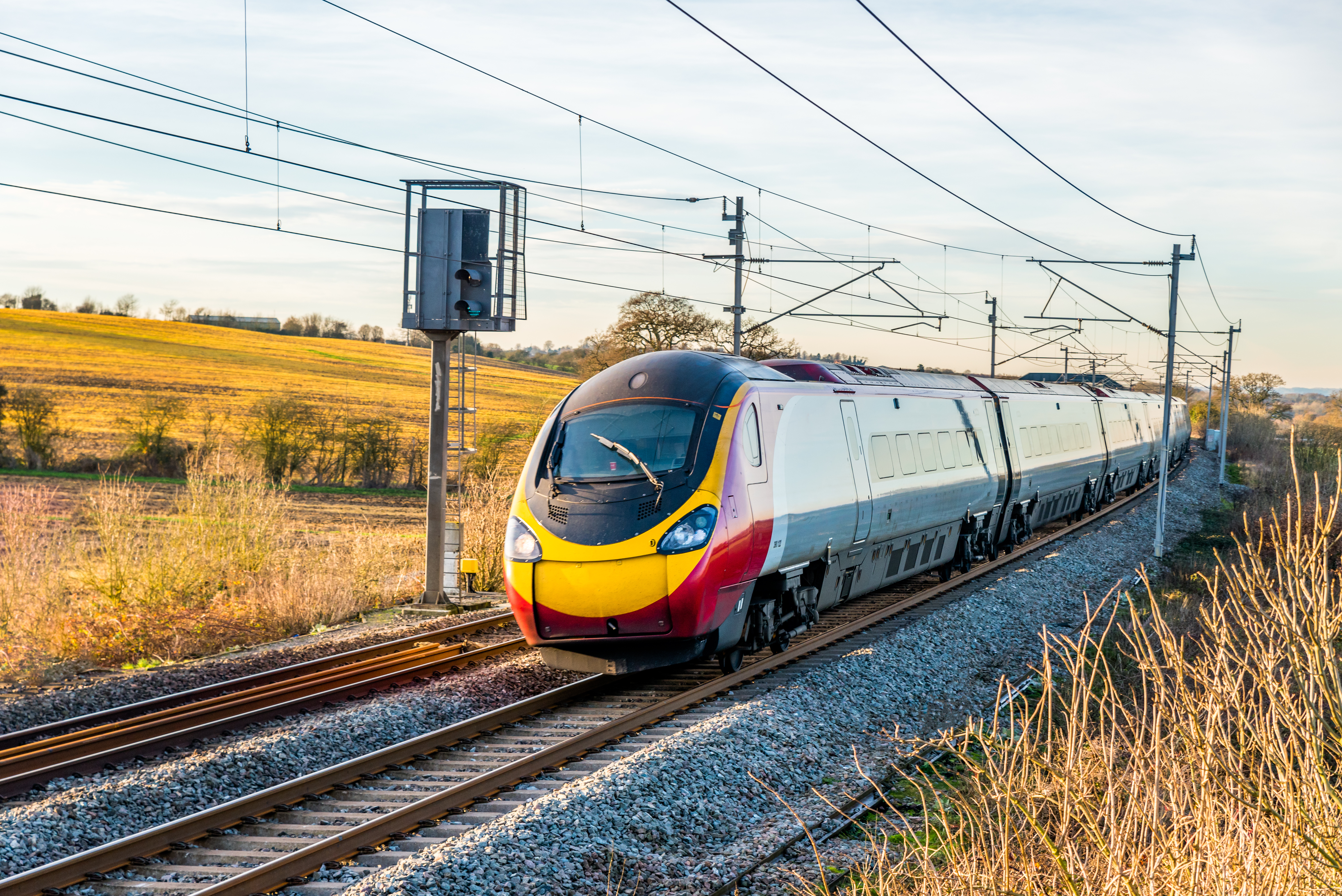 A train traveling on railway tracks, with the tracks stretching into the distance, surrounded by open landscape.