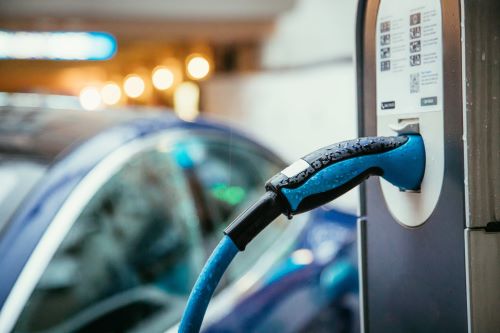 Close-up of an electric vehicle (EV) being charged, with a charging cable securely connected to the vehicle's port, located at the front side of the vehicle.